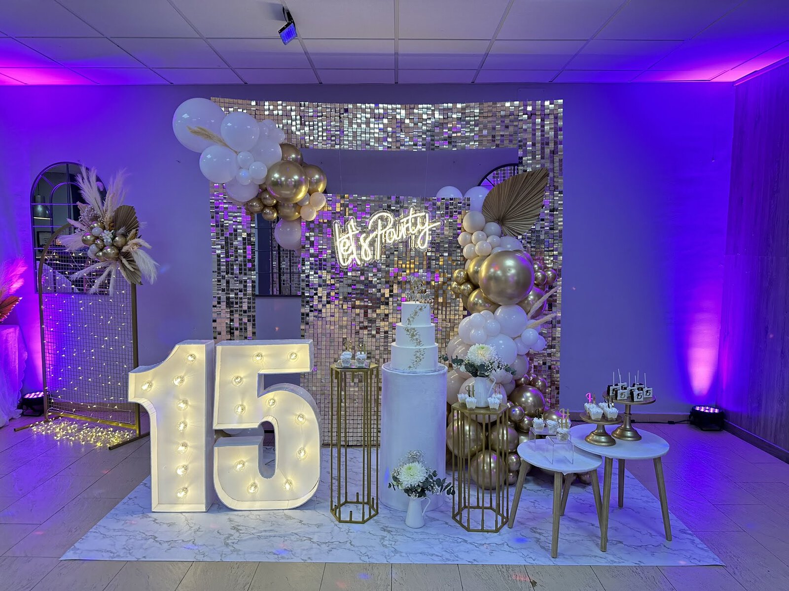 Ambientación de una fiesta de 15 con números luminosos, globos y mesa dulce